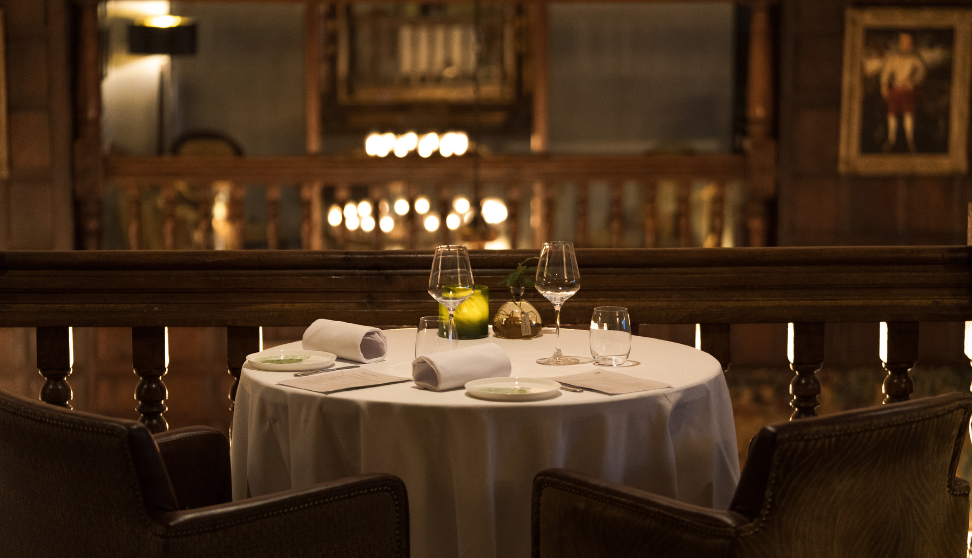 Two dining chairs with a table covered in a white drape with wine glasses on